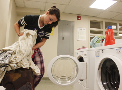 Sophomore fashion design major Anna McCann loads a laundry machine in Centennial Court E on Wednesday. She is pleased that students will have to pay a $40 laundry fee per semester instead of having laundry cards. That would be so nice because I know I have spent way over 40 bucks, McCann said. Photo by Jessica Yanesh.