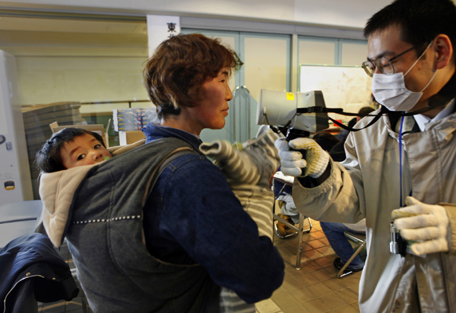At the Yamagata Sports Center, residents of Fukushima are screened for radiation when they check into the displaced persons center, Wednesday, March 16, 2011. Here, Yukiko Fushimi, center, gets checked along with her two grandchildren, but none of them showed elevated levels. (Carolyn Cole/Los Angeles Times/MCT)