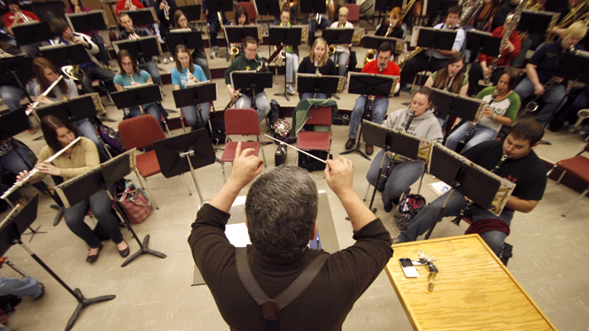 Marcus Neiman conducts the concert band during rehearsal at the Music and Speech Center on Thursday. The wind ensemble and concert band are hosting a free performance Sunday at 3:30 p.m. in the Cartwright auditorium. Photo by Nikolas Kolenich.