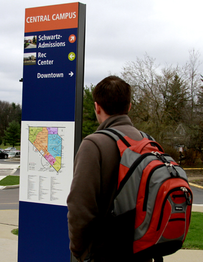 A student passes by a new Central Campus sign outside of the Michael Schwartz Center. This sign is part of a new initiatve to promote pedestrian movement. Photo by Lindsay Frumker.