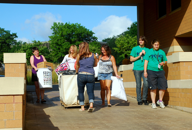 Moving is a group effort for Kent State students moving in on Thursday, Aug. 25. Whether enlisting the assistance from one’s family as Nicole Diederich, freshman exercise science major (2nd from left), did, or getting a hand from the Kent Interhall council’s Movers & Groovers (green shirts, far right), help moving in is never far away. Photo by Sam Verbulecz.