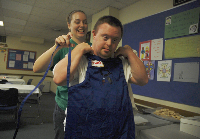 Ashleigh Stewart, of Youngstown, puts an apron on Chad Howe, of Kent at the third annual Power Corps spaghetti dinner on Sept. 9. Stewart has been with Power Corps for five years and has been the program manager for three. I love to see the interaction between members and participants, Stewart said. Photo by Nancy Urchak.