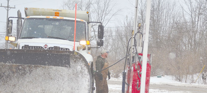 Matt Benson of Rootstown, OH looks off towards one of his co workers who plows the street next to where Benson refuels his own truck on Saturday, Janaury 13th. There is a special fuel tank of diesel specifically for the workers so they don’t have to pay for gas on their 16 hours of driving. Photo by Jacob Byk.