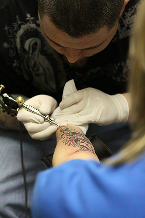 Jake Davis, of Smokin Tattooz on the corner of Main and Water street, finishes up a tattoo on Lauren Repp, 24, of Las Vegas on January 30. Photo by Coty Giannelli.