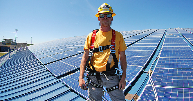 Tim McMillian, field manager from Third Sun Solar, stands on the roof of Kent State's field house on June 13. Third Sun Solar was contracted by Kent State to install the solar panels on the roof of the field house. Photo by Matt Hafley.