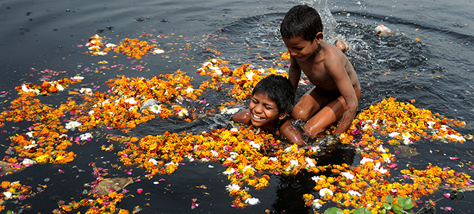 Children play and bathe in the Yamuna River as their mother washes clothes along the bank. The Yamuna River is a holy river that runs near the city of Delhi, India. The river has recently become an unsanitary spot in India due to the amount of defecating, washing and bathing that takes place in the river. Food is often washed in the Yamuna River as well, contributing to many food-born illnesses. Photos were taken on a study abroad trip in India. Photo by Kristin Bauer.