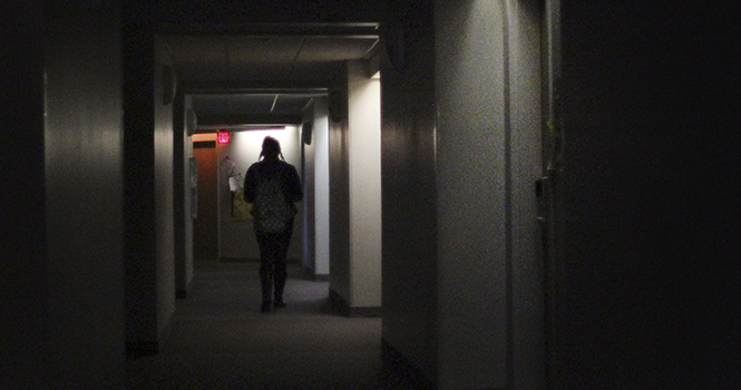 A resident of Centennial Court D walks through a darkened hallway on Oct. 18 with only the emergency lights on. The Kent area experienced sporadic power outages Thursday. Photo by BRIAN SMITH.