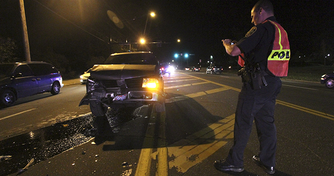 A Kent police officer photographs a car wreck on the corner of East Main Street and Midway Drive on Oct. 11. Photo by BRIAN SMITH.
