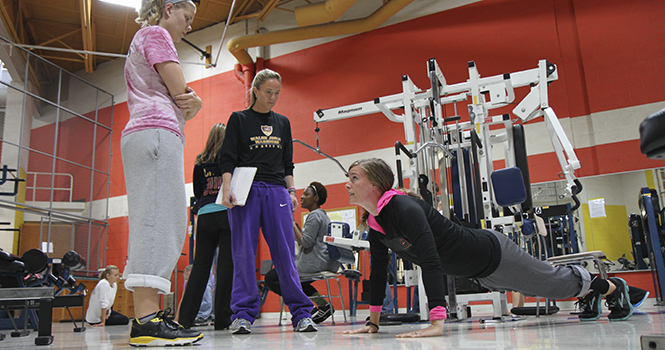 Kirsten Beverley, physical education instructor, demonstrates to her students the proper way to do a push-up during their exercise and weight control class September 27 in the Gym Annex. Photo by Shane Flanigan.