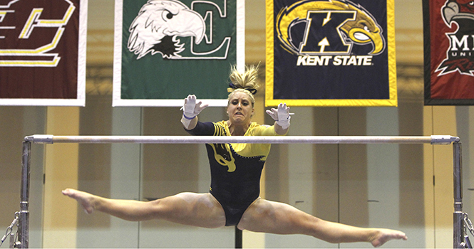 Sophomore Chelsea Drooger reaches out for the uneven bars Friday, Jan. 25 at the MACC during a tri-meet victory over Western Michigan and George Washington. Photo by Shane Flanigan.