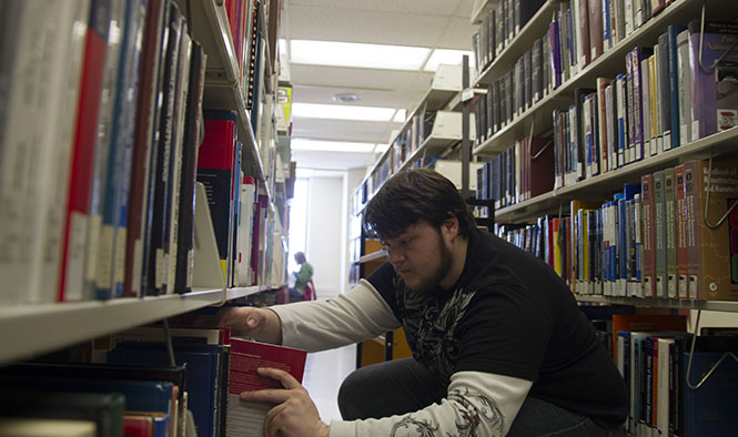 Junior industrial technology major Devon G. Roach shifts and organizes books in the library on Thursday, Feb. 7. Roach shelves books at the 7th floor, which collects a lot of science books that interest him. Photo by Yolanda Li.