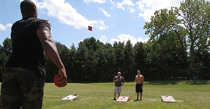 Darnell Sanders (left), former Cleveland Browns tight end, plays cornhole with Jason Welch (far right), owner of CrossFit Cadre in Hudson, at the third annual Adam Hamilton Scholarship Fund Memorial Cornhole Tournament on Saturday, August 3, 2013. Photo by Jessica White.