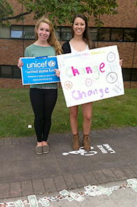 Freshmen fashion merchandising major Regina Dlwgosh and zoology major Megan Dunlap stand with signs near the UNICEF stand that has been posted on campus for several days, raising funds for efforts toward childrens well being in Syria. Photo by Carolyn Pippin.
