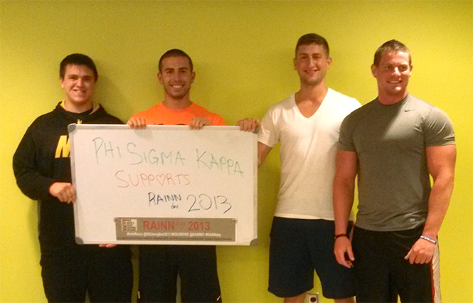 Active members of Phi Sigma Kappa (from left to right) Luke Deford, Justin May, Max Druiz, and Cody Lewis hold a sign from the 2013 Rainn Day event. Photo by Rachael Purget.