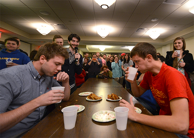 Ben Woolf, an international ambassador for Alpha Epsilon Pi from England (left), and Kent State senior physical education major Matthew Weaver (right) participate in a latke eating contest at AEPis annual LatkeFest at Hillel on Thursday, Nov. 21, 2013. Woolf defeated Weaver with a tie breaker, consuming a total of nine latke cakes. All of the fifth annual festivals funds will go to Save a Childs Heart, a cause that benefits children in need of transplants. Photo by Jenna Watson.