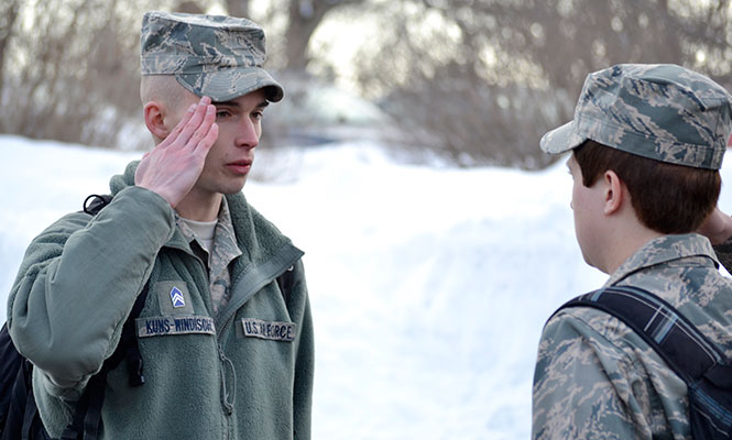 Cadet Tyler Kuns-Windisch salutes a fellow cadet before she falls into line to march from Terrace Hall to the M.A.C. Annex on Tuesday, Feb. 11, 2014.