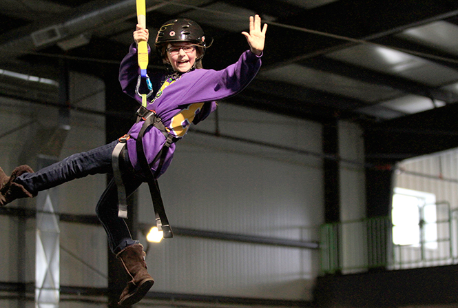 Isobella Leonardi, 9, waves to spectators on an observation deck while riding the zipline at Zip City, Sunday, Jan. 26, 2014. Zip City is the only indoor trampoline and zipline park in the world, located in Steetsboro, Ohio.