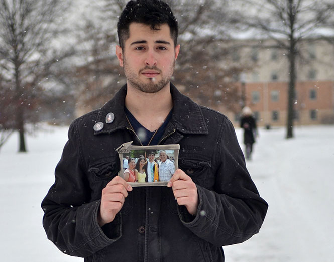 Kent State junior, Michael Fisher, holds a photo of him and his family from his high school graduation. Michael lives in Long Island, N.Y. which prevents him from making frequent travels home.