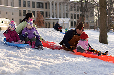 Parents Tiffany and Jake Der take their three children Katie, 3, and one year old twins Madeline and Emily sledding in the fresh snow Tuesday, Feb. 18, 2014.