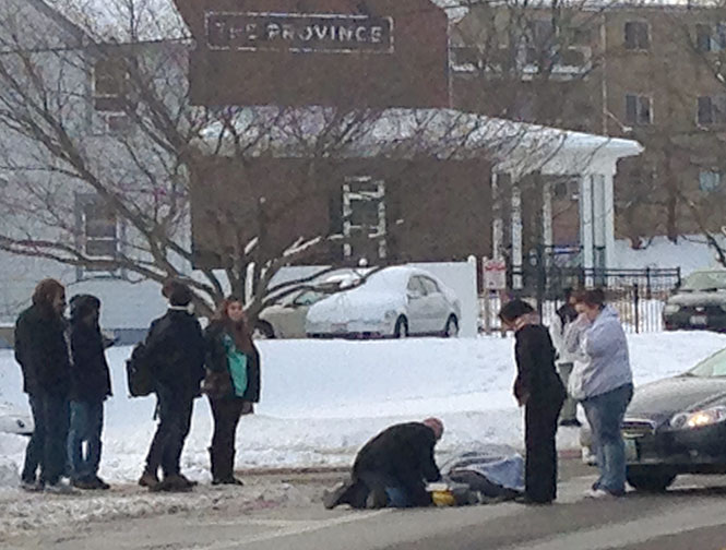 A pedestrian offers assistance after a woman was hit by a vehicle turning from Janik Drive on to Summit, striking her at the corner of Morris Road and Summit Street, around 4 p.m., Tuesday, Feb. 11, 2014.