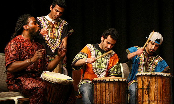 Term instructor of Pan-African studies Olu Manns (left) performs on stage with students from his Cultural Expressions class. Manns was quoted On the One referring to the diversity of students in his class being brought together from nations all across the world during the 19th annual African Night, Friday, March 14, 2014.