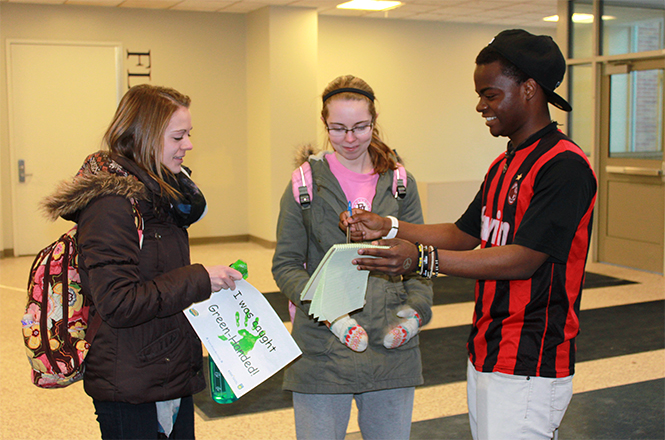 (Left) Conservation Club member Tanaka Mupinga catches and rewards students in the act of recycling during a Kent State Recyclemania sponsored event, Caught Green Handed, March 5, 2014. Members of the Conservation Club volunteered at the event, and plan to host more events of their own at Kent State in the near future. Photo courtesy of the Office of Sustainability