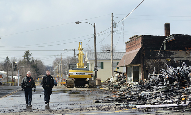 Two Garrettsville emergency personnel review damage along Main Street, Sunday, March 23, 2014, after the prior days fire burned 13 businesses to the ground.