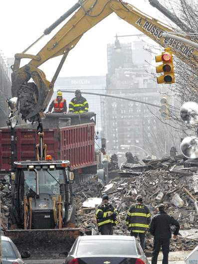 Debris is removed from a mound of rubble a day after a gas leak-triggered explosion, Thursday, March 13, in East Harlem, New York. Rescuers working amid gusty winds, cold temperatures and billowing smoke pulled additional bodies Thursday from the rubble of two apartment buildings that collapsed Wednesday.