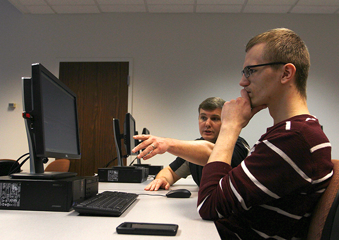 Senior Information Technology Support Analyst Thomas Clark gives a student instructions on the use of Adobe Premiere, Thursday, April 24, 2014.