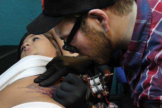 Tattoo artist Chase Ogle works on Morgan Dorskys tattoo on her side at Defiance Tattoos, April 7, 2014. Defiance Tattoos was voted best tattoo and piercing parlor in Kent.