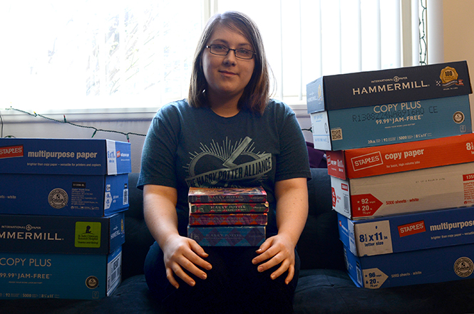 Graduate student Kara Whaley sits between the boxes of books her Harry Potter Alliance has collected to donate to charity.