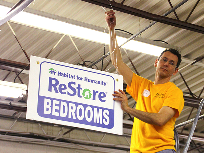 Kent State alumni Michael Bruder hangs up store signs as part of community service at the Habitat for Humanity ReStore on Saturday, April 12, 2014.