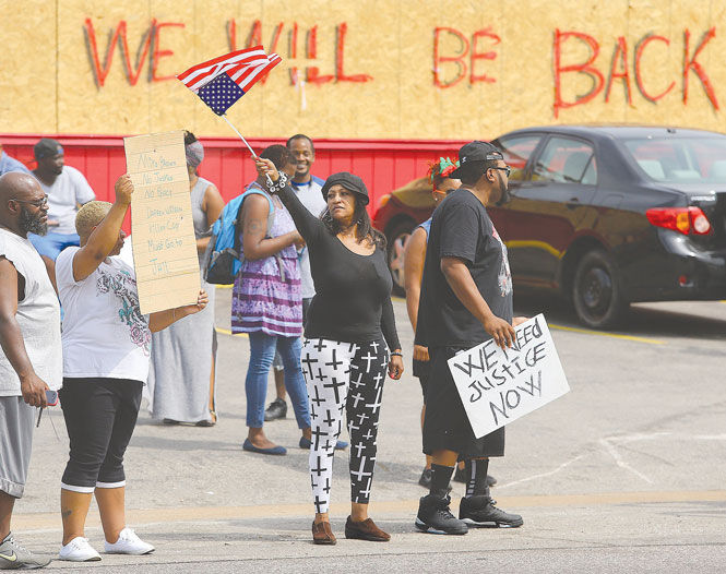A demonstrator waves an upside down American flag in front of a boarded up store on West Florissant Avenue on Wednesday, August 20, 2014, in Ferguson, Mo.
