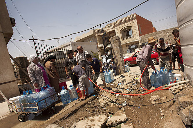 People line up to get water from a common well in Bartella, Afghanistan. Northern Iraq Christians have reason to worry about the self-proclaimed Islamic caliphate and many are seeking a safer place to live. 