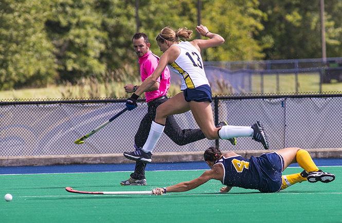 Kent State senior forward Hannah Faulkner fails to steal the ball as Michigans Mackenzie Ellis jumps to maintain possession at the field hockey game Sunday, Sept. 21, 2014. The Flashes lost to Michigan 3-2.