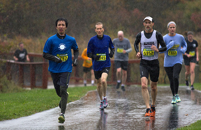 Runners Thanh Son Nguyen, 33, Phillip Nelson, 51, Paul Organ, 54, and Lauren Weinkauf, 22, bear the rain during the Bowman Cup 5k race Saturday, October 18, 2014.