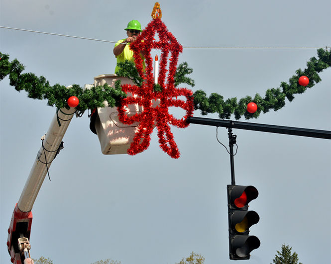 A municiple worker for the city of Kent hangs a wreath over the intersection of E Main St. and N Depeyster St on Tuesday, Oct. 28, 2014.
