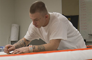 Shane Wadsworth, inmate at the Portage County Jail, draws a pattern on fabric for uniforms that will later be sewn together by inmates Thursday, Oct. 30, 2014.