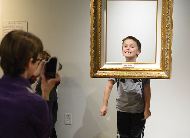 Max Kenworthy, age 7 from Kent, jumps into the air to get his head into an empty frame hanging in the new MuseLab art gallery in the School of Library and Information Science after putting the tag this is me on the frame Wednesday, Jan. 28, 2014.
