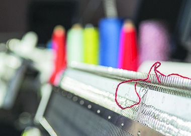 A strand of yarn on a knitting machine in the machine Knitting lab located in Rockwell hall on Tuesday, Feb. 10, 2015.
