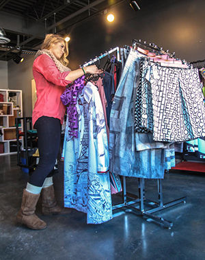 Alex Logsdon, a senior fashion merchandising major organizes clothing at the Kent State Fashion Store in Acorn Alley on Thursday Feb. 5, 2015.  I would love to work for Ralph Lauren someday said Logsdon who has been working at the store for almost a year.