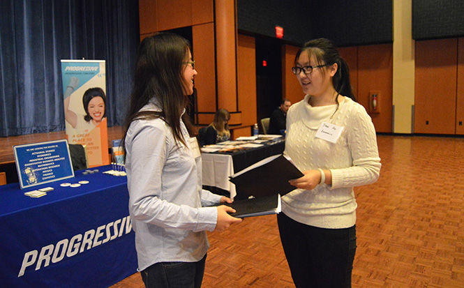 Applied mathematics major Yuanyuan Peng and economics major Yiwei Hu discuss the insurance companies they learned about at the Insurance Fair in the Kent State Student Center Ballroom on Wednesday Feb. 11, 2015. Students of all majors learned about possible career opportunities from different insurance companies at tables.