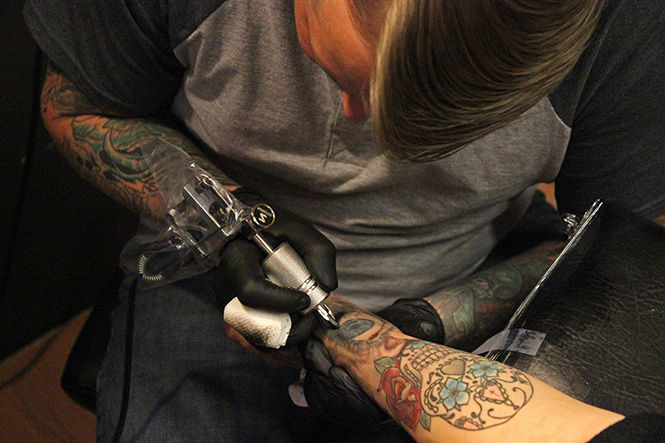 Owner Jay Miller works on fine arts major and apprentice Eliza Millers arm piece at Crucible Tattoos on Tuesday, March 17, 2015. Eliza first got the piece when she started her apprenticeship there.