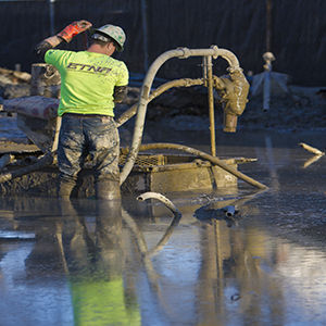 A worker stands in a foot of mud and water along the Esplanade as work begins on the new building for the College of Architecture and Environmental Design on Wednesday, March 11, 2015.