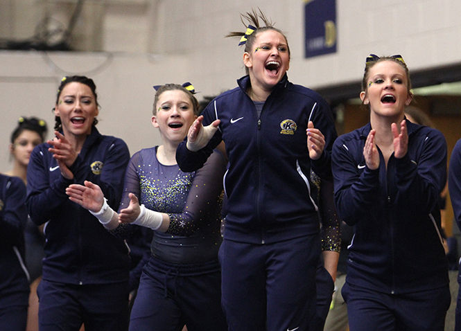  Kent State gymnasts cheer as their teammate lands a dismount off the vault during a meet against Central Michigan on Sunday, Feb. 15, 2015.