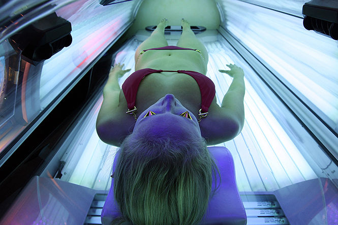 Erika Greet, an employee of U-Tan, a tanning salon located near USC, demonstrates for a photographer the workings of an Ergoline Excellence tanning bed.