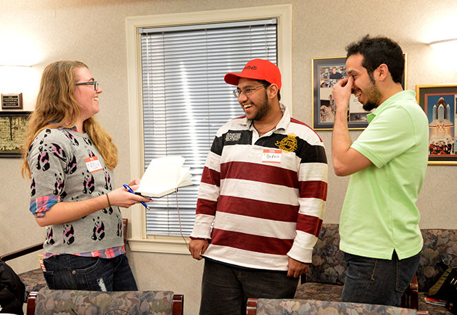 Missy Hendrix, a public health major, passes a book to students Baraa Iskandar and Abdullah Almotairi at the Kent State International Student Mentor’s meeting on March 3, 2015. Members of the organization can leave a message in their language in the journal to share with the group.