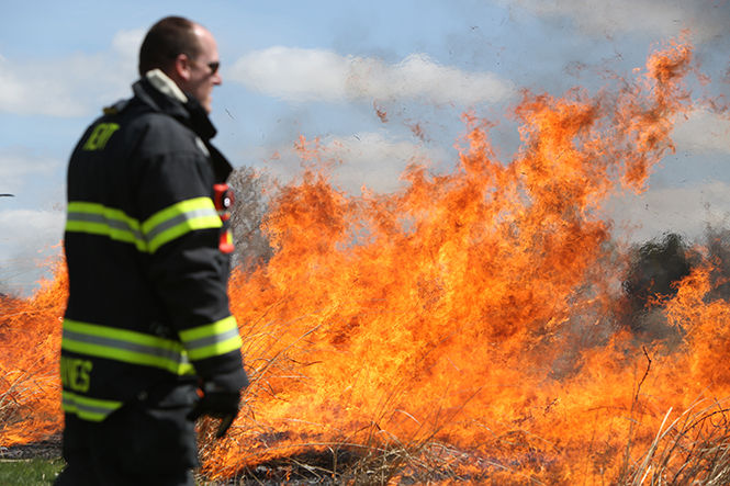 A controlled fire, started by the Kent Fire Department, rages on as firefighters keep watch on Tuesday, April 28, 2015. Every year the prairie grass behind the Student Wellness and Recreation Center is set on fire to keep the growth under control.