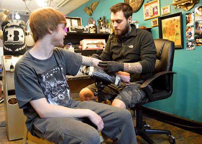 Artist Larry Spano begins to tattoo his client Chris Szabet at Defiance Tattoos and Piercing in Downtown Kent on April 6, 2015. Szabet is getting the phases of the moon tattooed on his forearm.