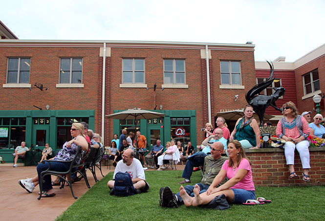 People sit and watch Jake Friel & The Last Train South perform at Acorn Alley Plaza during Kent Blues Fest on Friday, July 17, 2015.